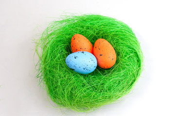 Colored easter eggs lie in a green nest isolated on white background
