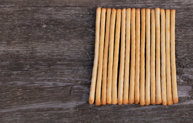Tasty Italian bread sticks on wooden background with copy space