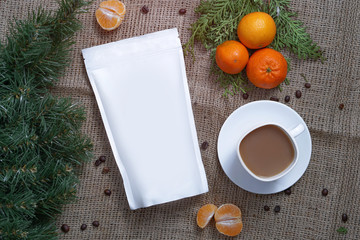 Template of paper ecological bag for storing coffee, tea on a background of texture and a cup of cappuccino with tangerines. Vacuum packaging for christmas and new year present