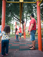 Asian family playing in the monkey bar playground in the morning.