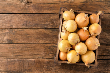 Fresh white onions in box on rustic wooden background with copyspace. Top view