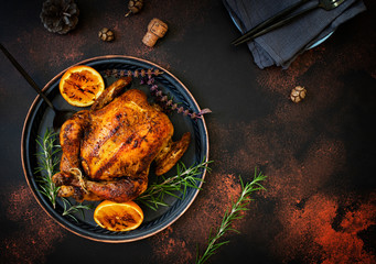 Baked whole chicken with oranges and rosemary. Tray with a festive Christmas dish on a dark rustic...