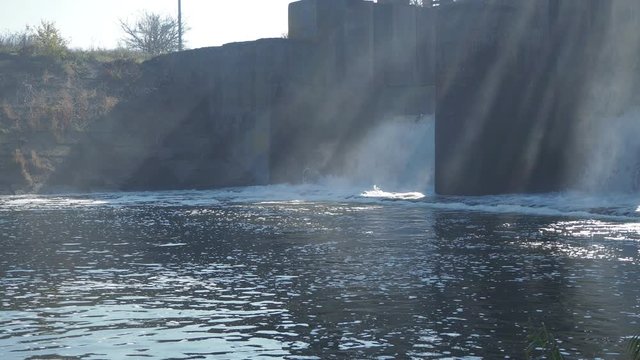 Water flow drop through the dam fog and sun