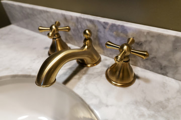 Sink made of expensive marble stone. Golden design of faucet and taps