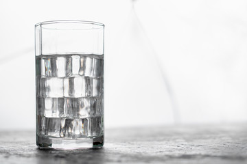 Glass of water with ice and light blurred background