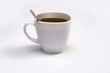 White cup of coffee with a spoon on an isolated background. Black cappuccino drink in a bowl