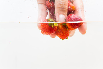 Hand pick up fresh strawberry fruit in water