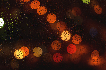 Out of focus lights through the car window on a rainy night.