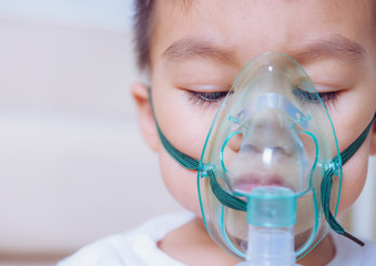 Closeup asian face little children boy using steam inhaler nebulizer mask inhalation
