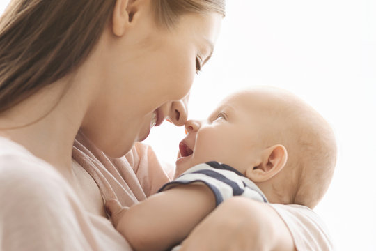 Young woman tenderly touching noses with her cute baby boy