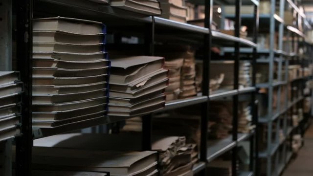 Bookshelves in an old library or archive room. Old room with books and documents with a basement light. Footage for the concept of training and historical news.
