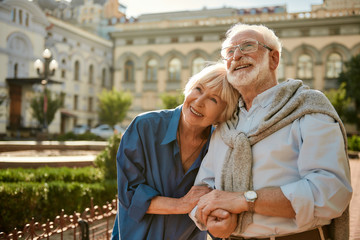 We love to travel together. Happy senior couple bonding to each other and smiling while standing outdoors - Powered by Adobe