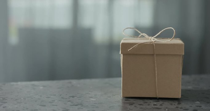 Slow motionbrown paper gift box slide in frame on terrazzo countertop