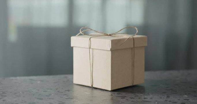 Slow motionbrown paper gift box slide in frame on terrazzo countertop