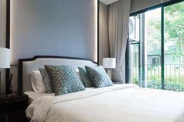 Double bed. Interior bedroom in a hotel with turquoise blue mood and tone decoration. Window light. Selective focus on the pillows.