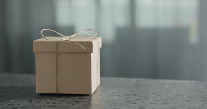 Slow motionbrown paper gift box slide in frame on terrazzo countertop