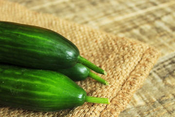  Bright fresh cucumbers lie on a rag bag. Wood background. Close-up.