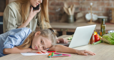 Little girl suffering from mom indifference, laying on kitchen table