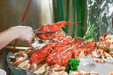 Lobster. A hand holding a giant lobster at a seafood buffet. Soft focus on the lobster.