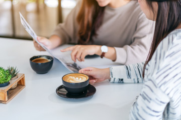Closeup image of people talking, reading newspaper and drinking coffee  together in the morning