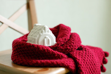 house model toy. Warm house concept, Heating efficiency. environmentally friendly warm home wrapped in a soft comfortable scarf