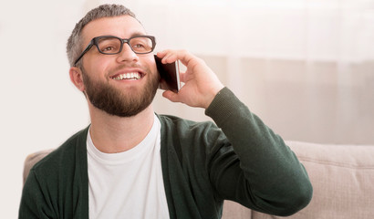 Man talking on smartphone at home and smiling