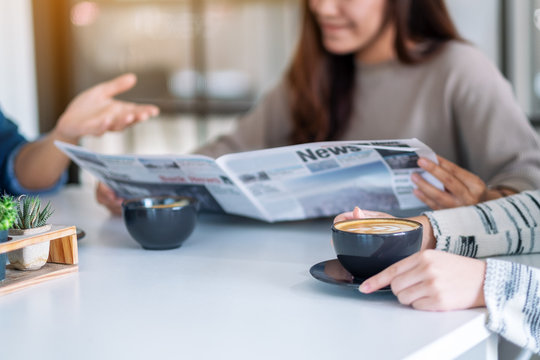 Closeup image of people talking, reading newspaper and drinking coffee  together in the morning