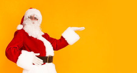 Fototapeta na wymiar Santa Claus holding hand for your text over orange background
