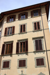 Obraz premium Facade of house with yellow wall, windows with brown shutters in Firenze, Italy.