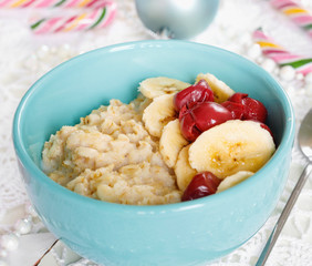 Christmas holiday breakfast. Oatmeal with bananas, cherries and sweets in beautiful bowl