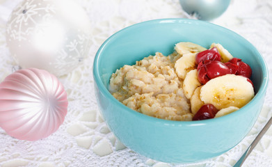 Christmas holiday breakfast. Oatmeal with bananas, cherries and sweets in beautiful bowl