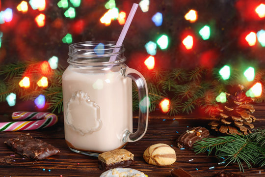 Glass cup of hot cocoa with milk, cinnamon, candies and  straw tube