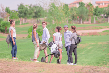 A group of young friends chatting on a golf course on a sunny day with the background out of focus. Concept of a day of relaxation.