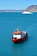 boat in the bay of the Eqip Sermia with icebergs  - melting Eqi Glacier in Greenland Disko Bay,  World of greenland travel - global warming and climate change. Summer, July © Friederike