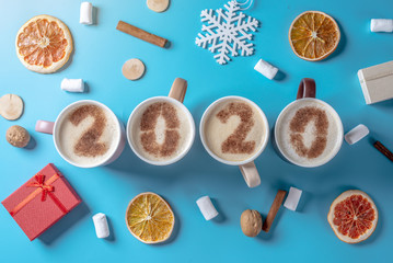 Card with numbers 2020 for New year and Christmas. Cup of coffee with figures on blue background. Top view. Flat lay