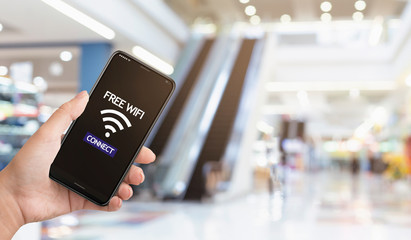 Hand holding smartphone connected to free wifi in shopping center