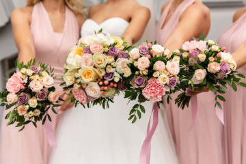 Bride and bridesmaids in pink dresses posing with bouquets at wedding day. Happy marriage and wedding party concept - obrazy, fototapety, plakaty
