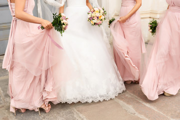 Obraz na płótnie Canvas Bride and bridesmaids in pink dresses having fun at wedding day. Happy marriage and wedding party concept