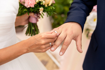 Obraz na płótnie Canvas Wedding, marriage concept. Bride puts wedding ring on groom’s finger on wedding day