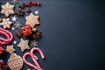 Christmas composition, New Year greeting card. Mockup with festive food decorations and gingerbread cookies on black background. Copy space.