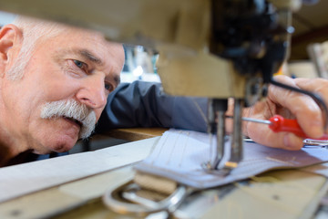 senior workman sewing on stitch lathe