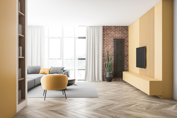 Fototapeta premium Brick and yellow living room with sofa and TV