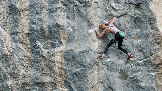 young woman climber climbs a rock