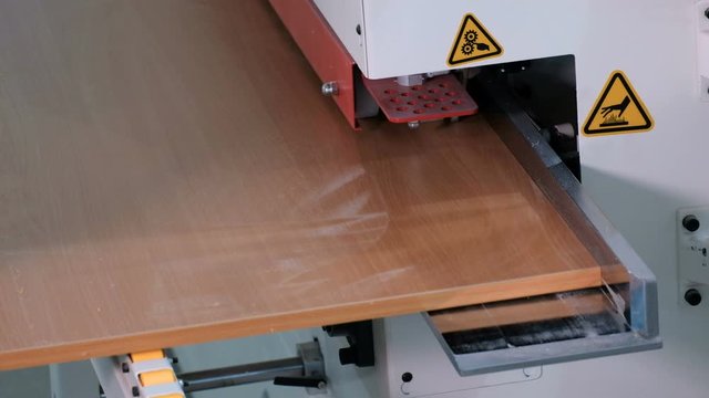 Men's hands on an electric machine for gluing edges on chipboard. A person observes safety precautions at work. Industrial production of furniture parts. Video with the original sound of noise. Furnit