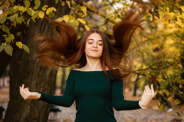 Autumn girl portraits. Emerald dress. Yellow leaves and trees. Park. Warm atmosphere.