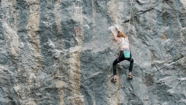 young woman climber climbs a rock
