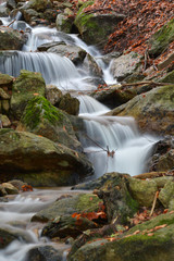 Fototapeta premium La cascata tra le rocce del bosco in autunno