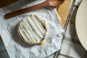 Top view on grilled Camembert cheese head on plate and on cutting board. light texture background. Tasty food for breakfast.