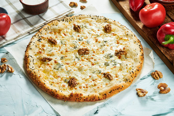 Italian fresh four cheese pizza with walnuts on a light background. Composition with pizza, sauce and tomatoes. Top view with copy space. Flat lay. quattro fromaggi