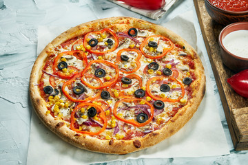 Homemade oven-baked pizza vegetarian with onions, olives, tomatoes, corn red sauce. Composition with crispy pizza, tomatoes on a light background